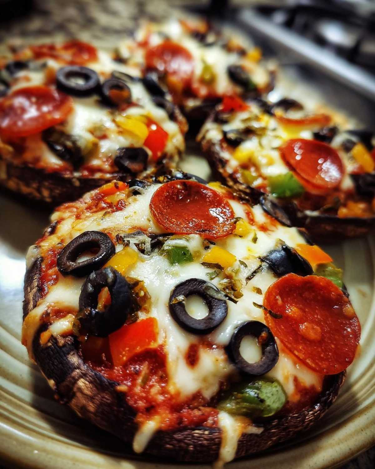 Close-up of a Keto Pizza Stuffed Portobello Mushroom topped with melted mozzarella, pepperoni, olives, and peppers.