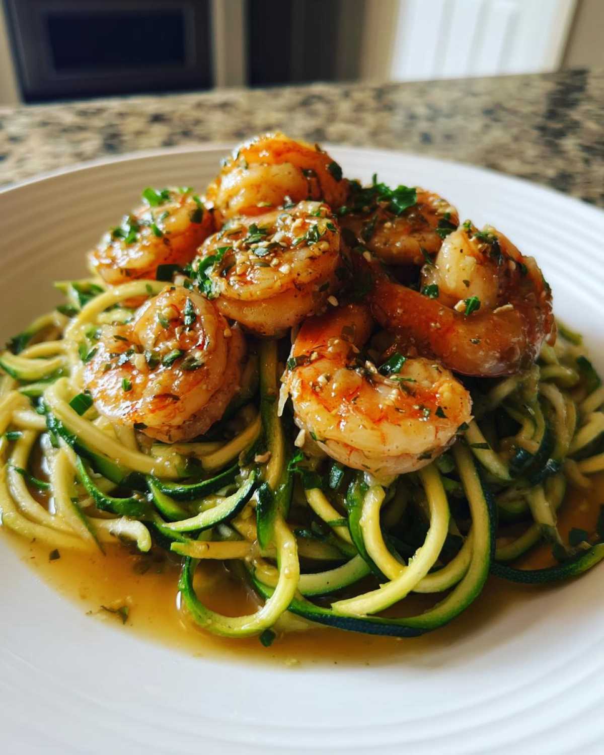 A close-up of Keto Shrimp Scampi Zucchini Noodles served on a white plate, topped with plump shrimp in garlic butter sauce.