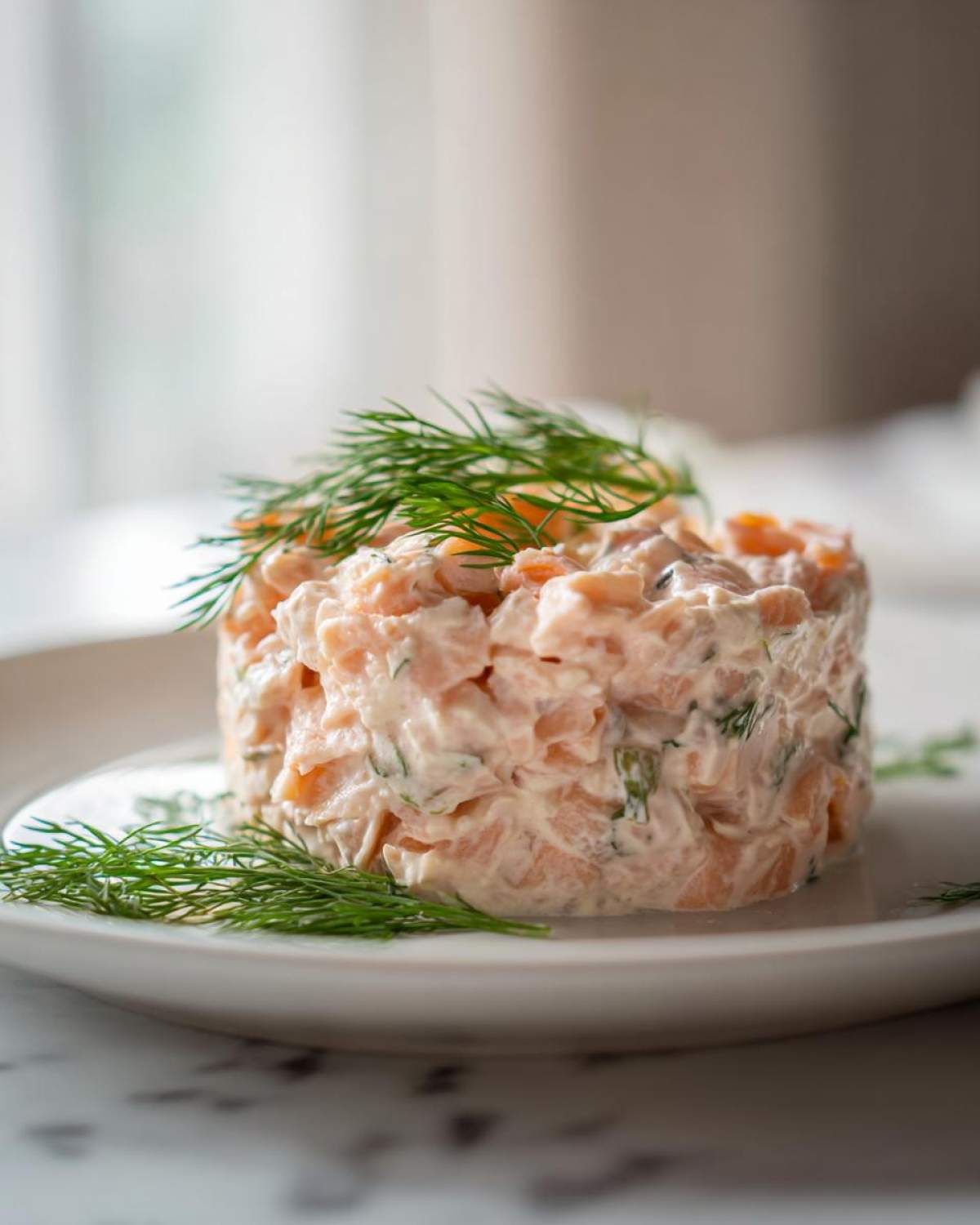A molded portion of creamy salmon salad, garnished with fresh dill sprigs, ready to serve.
