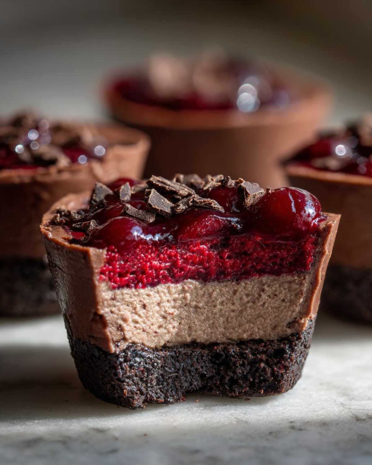 Close-up of a No-Bake Chocolate Cherry Cheesecake Cup cut in half showing layers.
