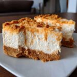 Two slices of creamy No-Bake Orange Creamsicle Cheesecake Bars with a thick graham cracker crust and orange crumble topping.