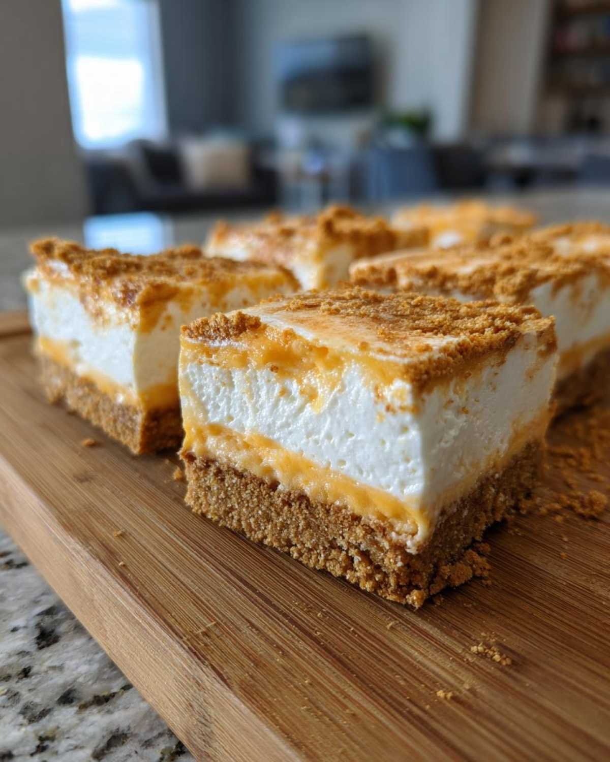 Close-up of several No-Bake Orange Creamsicle Cheesecake Bars squares on a wooden cutting board.