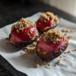 Three No-Bake Strawberry Cheesecake Stuffed Dates topped with graham cracker crumbs on parchment paper.