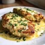 Two golden-brown One-Pan Creamy Garlic Butter Turkey Cutlets smothered in a rich, yellow cream sauce and topped with fresh parsley.