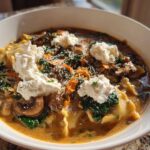 A close-up of a bowl of One-Pot Creamy Spinach Mushroom Lasagna Soup topped with dollops of ricotta cheese.