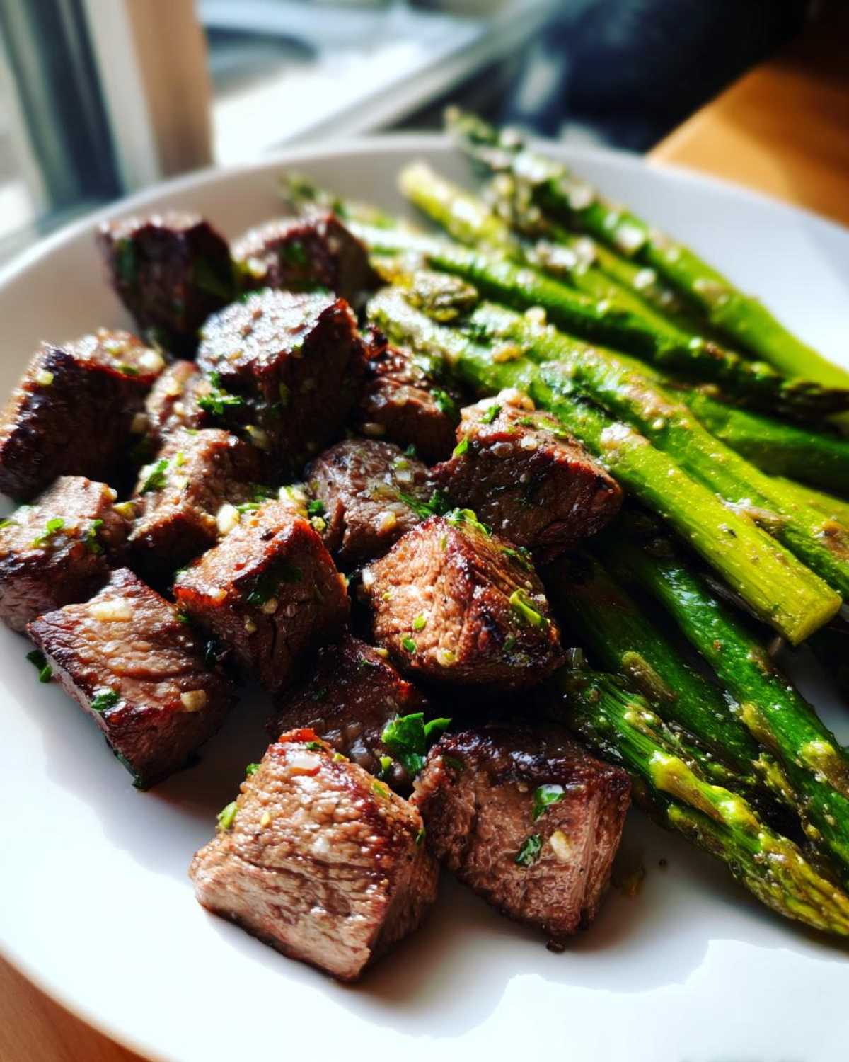 Close-up of juicy steak bites and roasted asparagus from Sheet Pan Garlic Butter Steak and Asparagus.