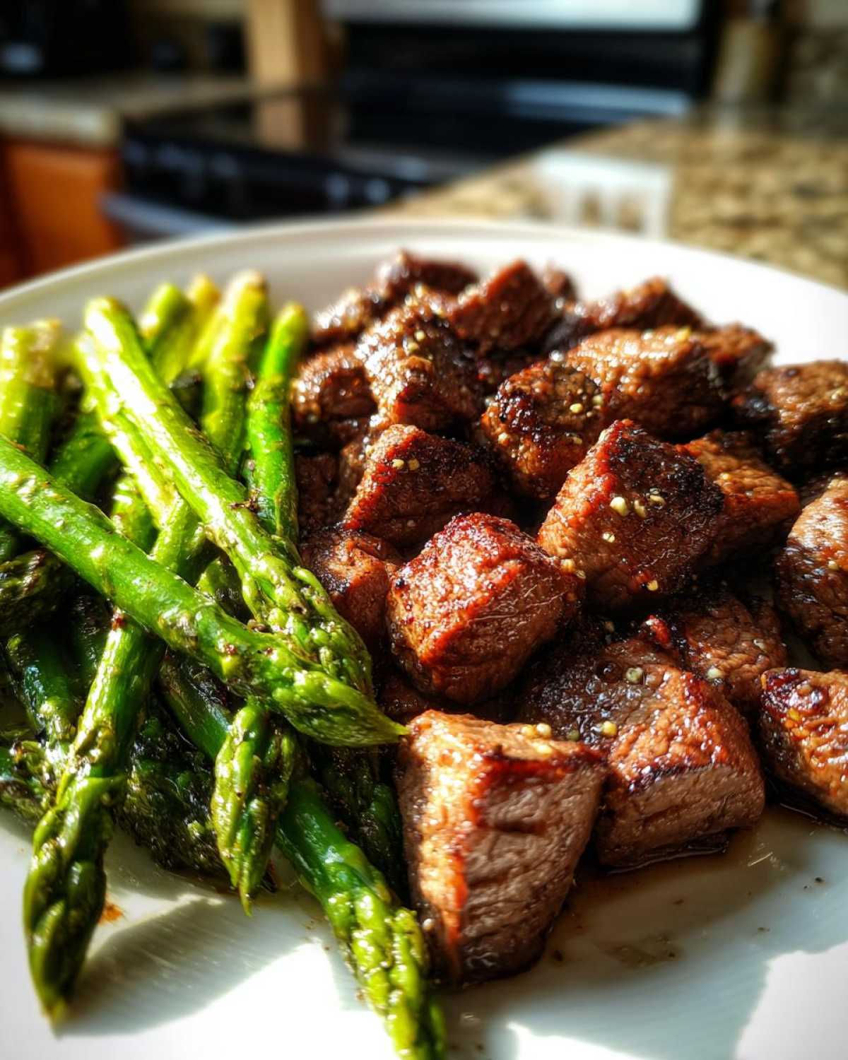 Close-up of juicy steak bites and bright green asparagus from Sheet Pan Garlic Butter Steak and Asparagus.