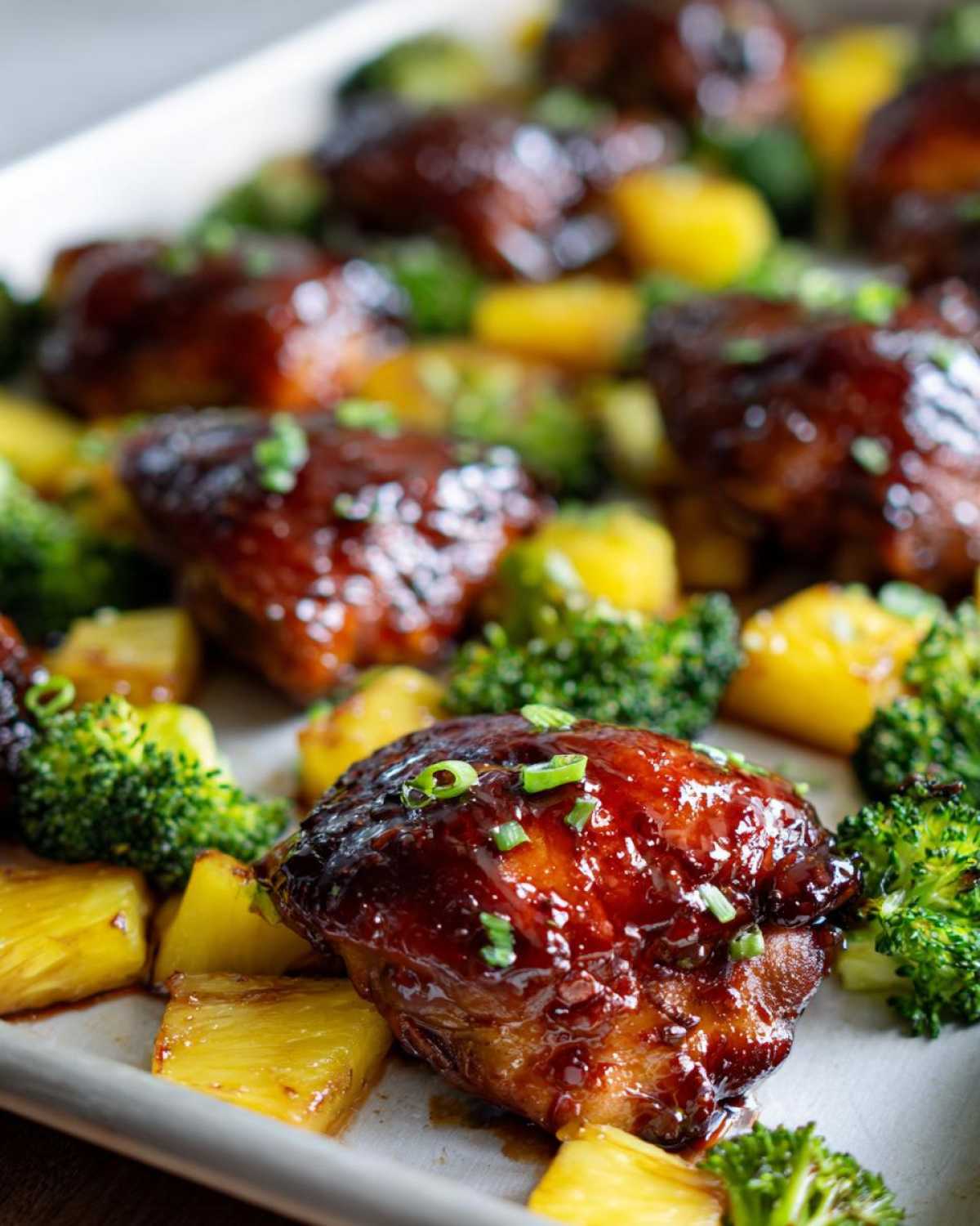 Close-up of glazed Sheet Pan Teriyaki Chicken Thighs with Pineapple chunks and broccoli florets.