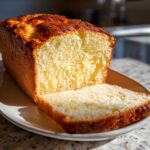 A loaf of soft, golden-brown condensed milk bread with one slice cut and resting against the main loaf.