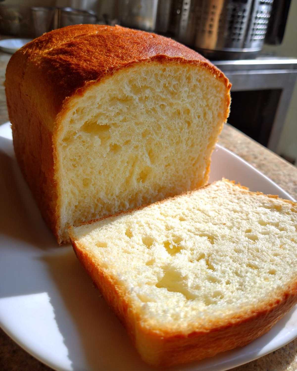 Close-up of a freshly baked loaf of condensed milk bread, showing a soft, fluffy interior crumb and golden crust.