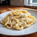 A close-up of fettuccine pasta generously coated in rich Vegan Creamy Cashew Alfredo Sauce, seasoned with pepper.