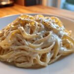 Close-up of fettuccine pasta generously coated in Vegan Creamy Cashew Alfredo Sauce and topped with black pepper.