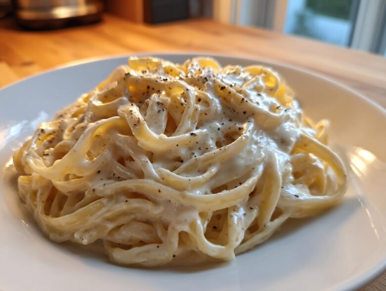 Close-up of fettuccine pasta generously coated in Vegan Creamy Cashew Alfredo Sauce and topped with black pepper.