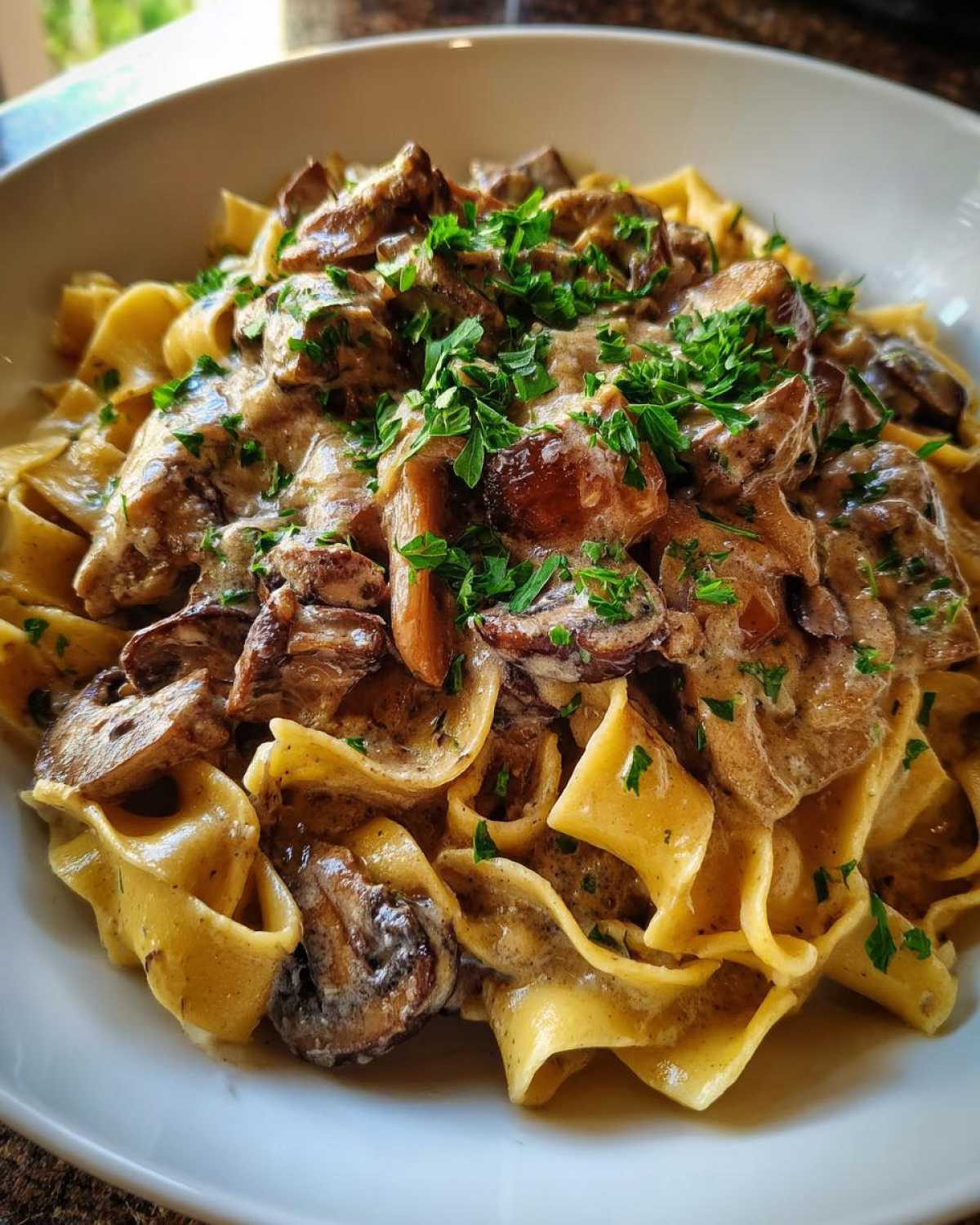 Close-up of Vegan Mushroom Stroganoff served over wide egg noodles and garnished with fresh parsley.