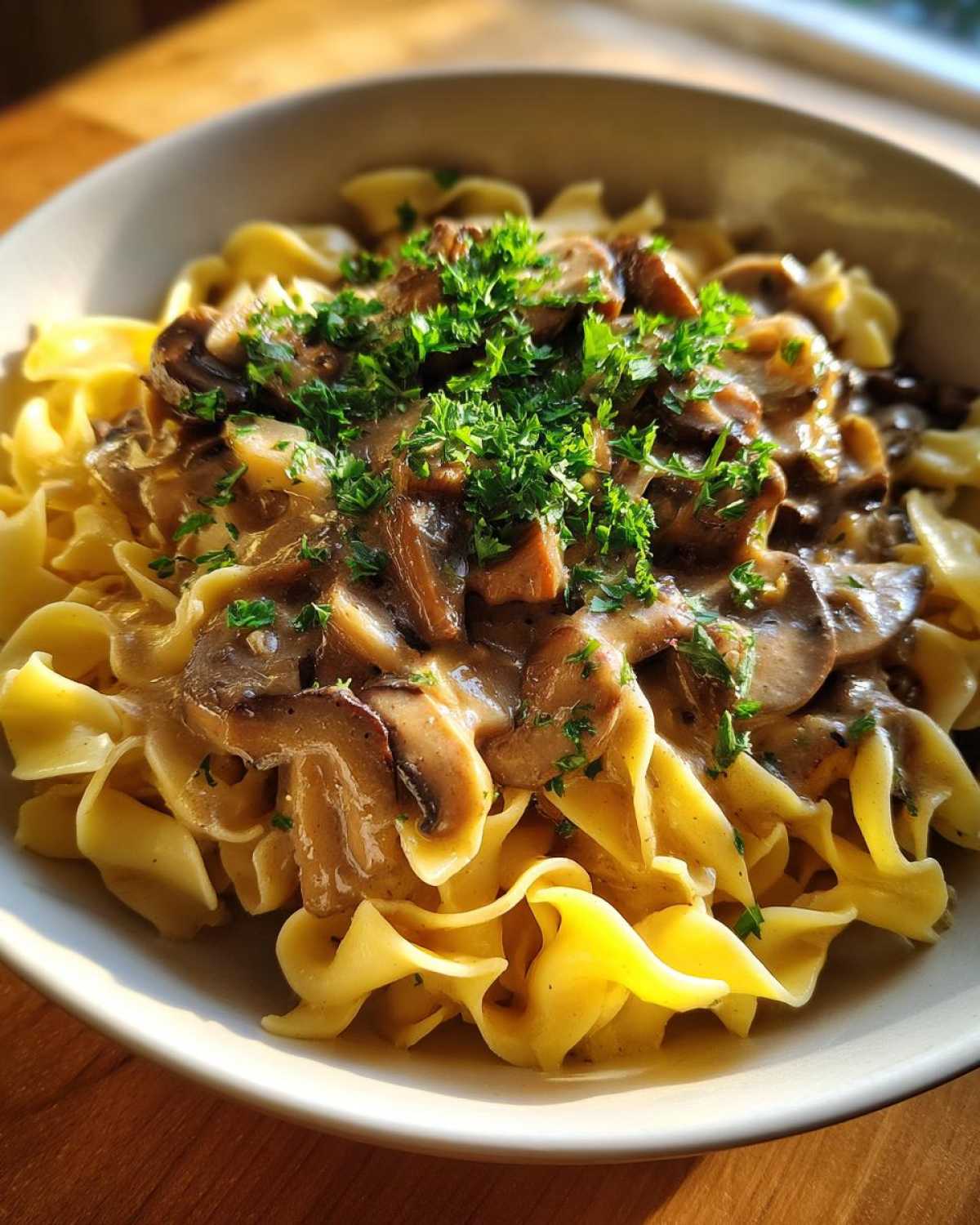 Close-up of Vegan Mushroom Stroganoff served over wide egg noodles and garnished with fresh parsley.