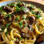 Close-up of creamy Vegan Mushroom Stroganoff served over fettuccine pasta and garnished with fresh parsley.