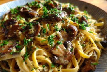 Close-up of creamy Vegan Mushroom Stroganoff served over fettuccine pasta and garnished with fresh parsley.