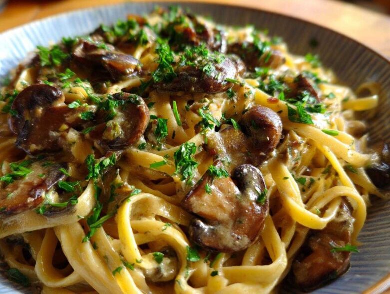 Close-up of creamy Vegan Mushroom Stroganoff served over fettuccine pasta and garnished with fresh parsley.
