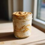 A glass jar filled with Vegan Peanut Butter Banana Overnight Oats, swirled with peanut butter.