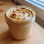 Close-up of creamy peanut butter mixture topping for Vegan Peanut Butter Banana Overnight Oats in a glass jar.