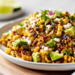 Close-up of Charred Grilled Corn Salad featuring charred corn kernels, avocado chunks, crumbled Cotija cheese, and cilantro.