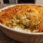 Close-up of a baked Cheesy Summer Squash Casserole in a white dish with a golden brown, crunchy breadcrumb topping.