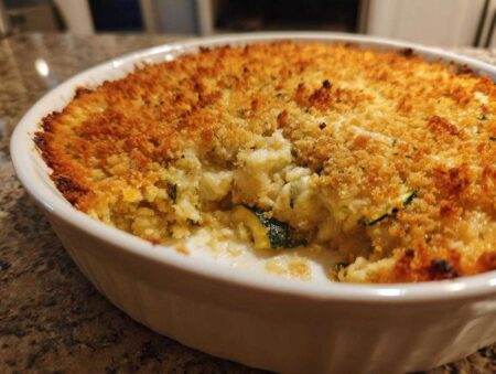 Close-up of a baked Cheesy Summer Squash Casserole in a white dish with a golden brown, crunchy breadcrumb topping.