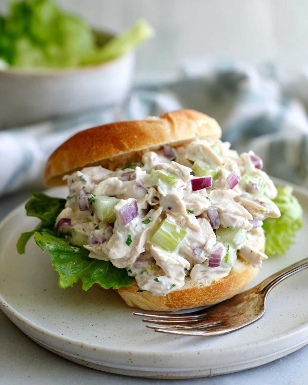 A generous serving of Classic Chicken Salad for Sandwiches piled high on a soft bun with lettuce.