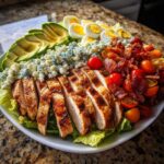 A vibrant platter of Classic Cobb Salad with Grilled Chicken, featuring sliced chicken breast, avocado, blue cheese, bacon, and eggs.