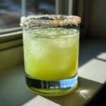 A refreshing Classic Margarita on the Rocks with Salt Rim, showing condensation and ice cubes in a glass.