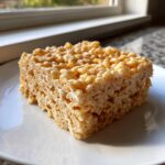 A single, thick square of Classic Rice Krispie Treats Squares sitting on a white plate.