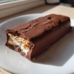 A close-up of a Dubai Chocolate Bar Ice Cream Bars, showing the cracked chocolate shell and creamy white filling with biscuit layers.