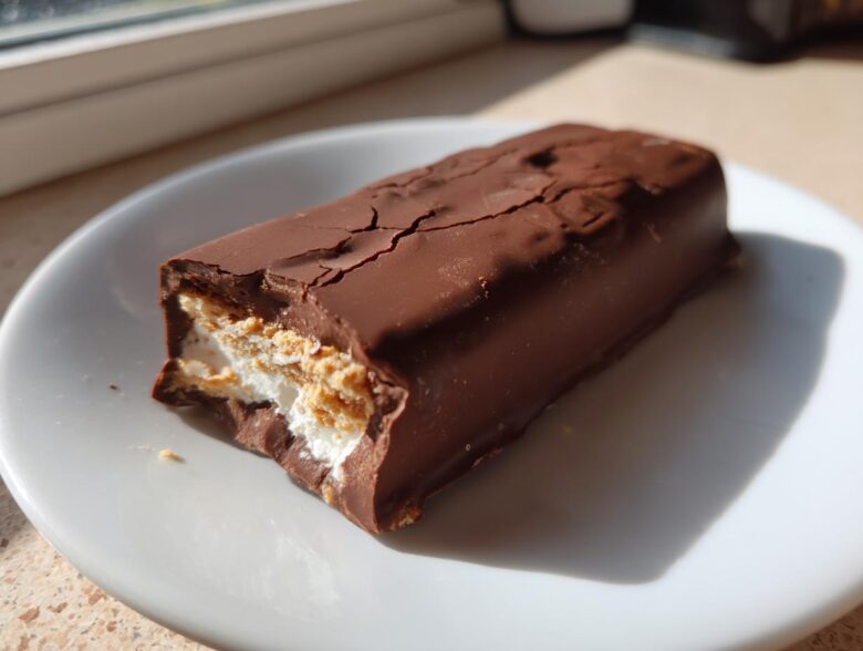 A close-up of a Dubai Chocolate Bar Ice Cream Bars, showing the cracked chocolate shell and creamy white filling with biscuit layers.