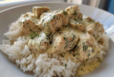 Close-up of tender chicken pieces covered in creamy tzatziki sauce with dill, served over white rice, ready for the Dump-and-Bake Chicken Tzatziki Recipe.
