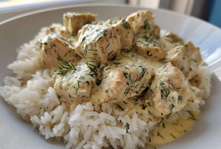 Close-up of tender chicken pieces covered in creamy tzatziki sauce with dill, served over white rice, ready for the Dump-and-Bake Chicken Tzatziki Recipe.