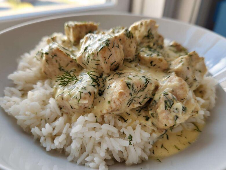 Close-up of tender chicken pieces covered in creamy tzatziki sauce with dill, served over white rice, ready for the Dump-and-Bake Chicken Tzatziki Recipe.