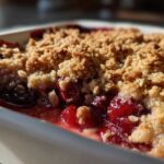 Close-up of a golden, crumbly topping over bubbling red cherries in an Easy Cherry Crisp.