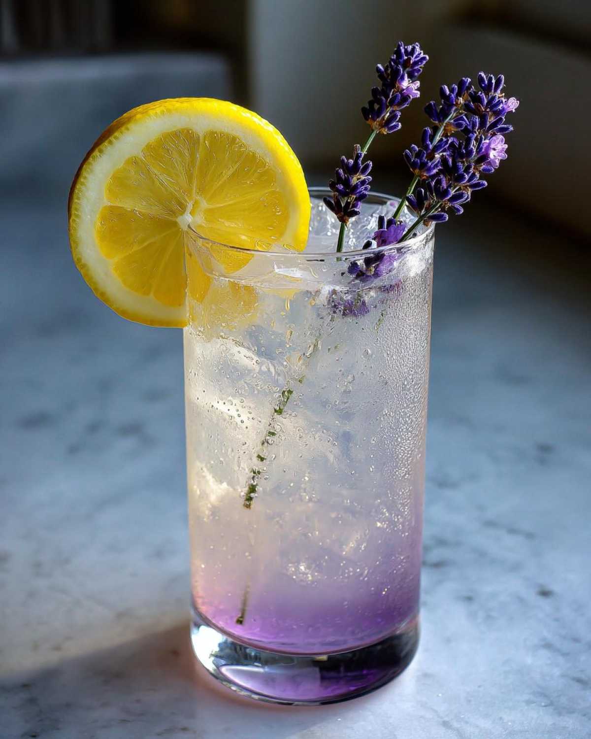 Close-up of a tall glass of Fragrant Lavender Lemonade with ice, garnished with a lemon wheel and fresh lavender sprigs.