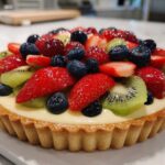 A vibrant, finished Fresh Fruit Tart with Vanilla Pastry Cream topped with strawberries, blueberries, and kiwi slices.