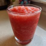 Close-up of a vibrant red, icy Frozen Strawberry Daiquiri Recipe served in a clear glass.
