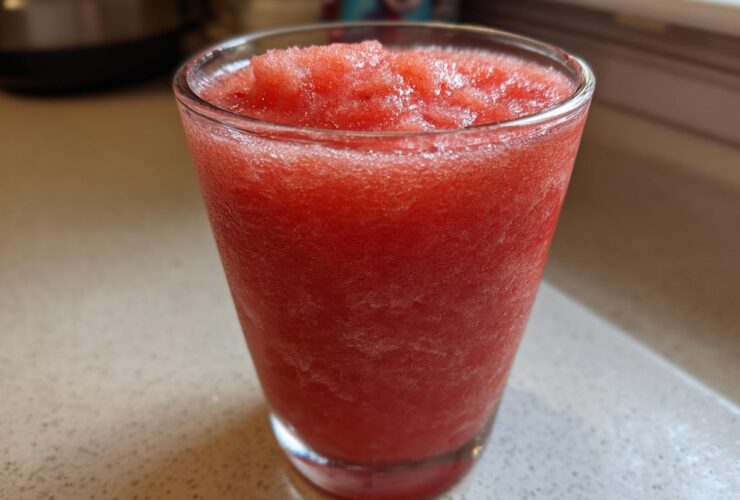Close-up of a vibrant red, icy Frozen Strawberry Daiquiri Recipe served in a clear glass.