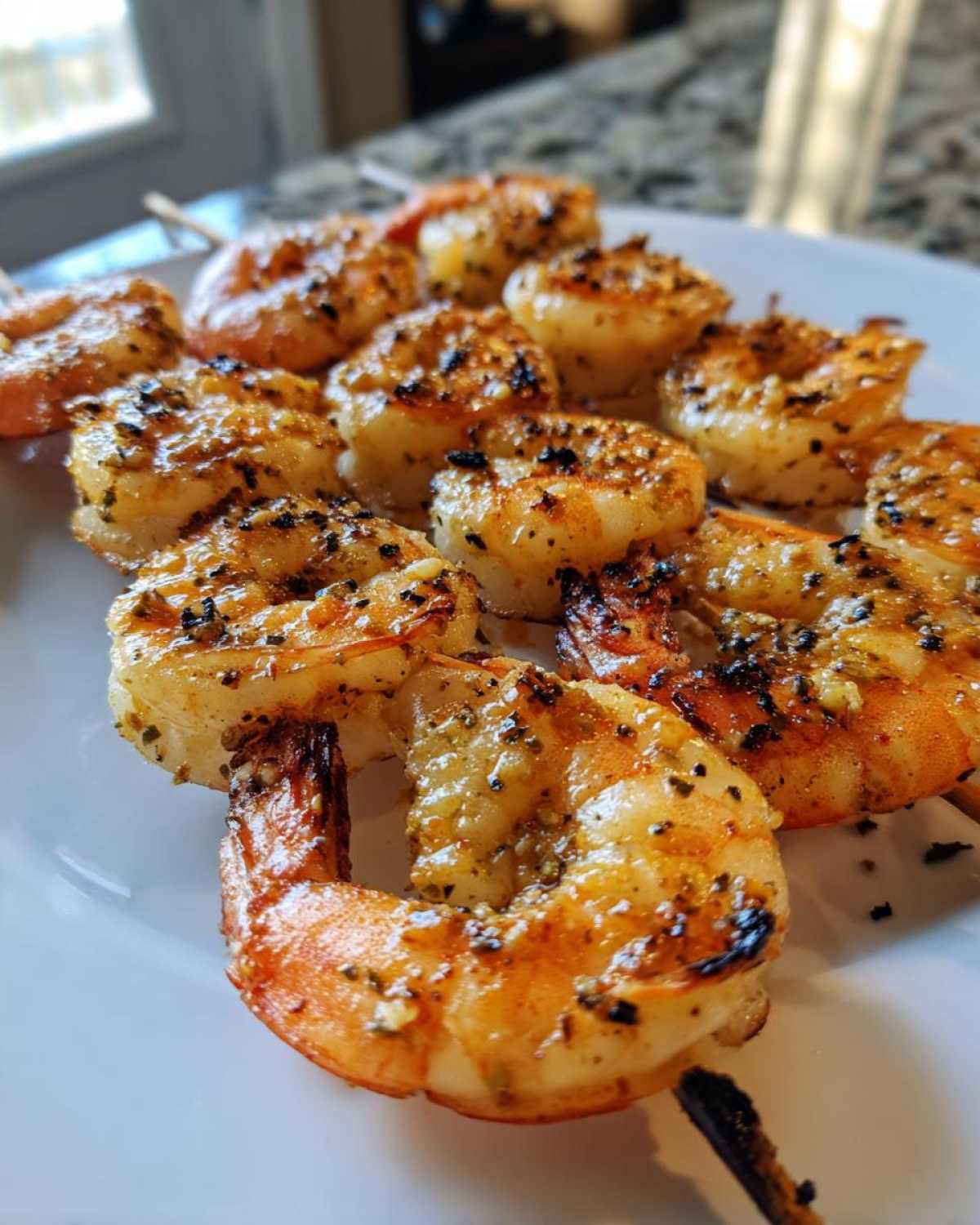 Close-up of perfectly grilled Garlic Butter Grilled Shrimp Skewers seasoned with black pepper, served on a white plate.