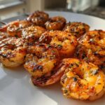 Close-up of several juicy Garlic Butter Grilled Shrimp Skewers resting on a white plate, glistening with butter and herbs.