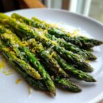 Close-up of perfectly Grilled Asparagus Spears with Parmesan and Lemon zest on a white plate.