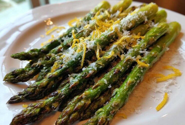 Close-up of perfectly Grilled Asparagus Spears with Parmesan and Lemon zest on a white plate.