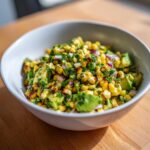 Close-up of vibrant Grilled Corn and Avocado Salsa mixed with red onion and cilantro in a white bowl.