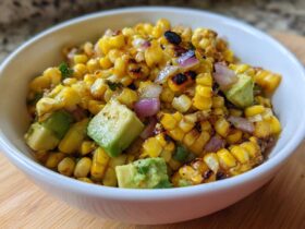 A white bowl filled with vibrant Grilled Corn and Avocado Salsa, featuring charred corn kernels and chunks of green avocado.