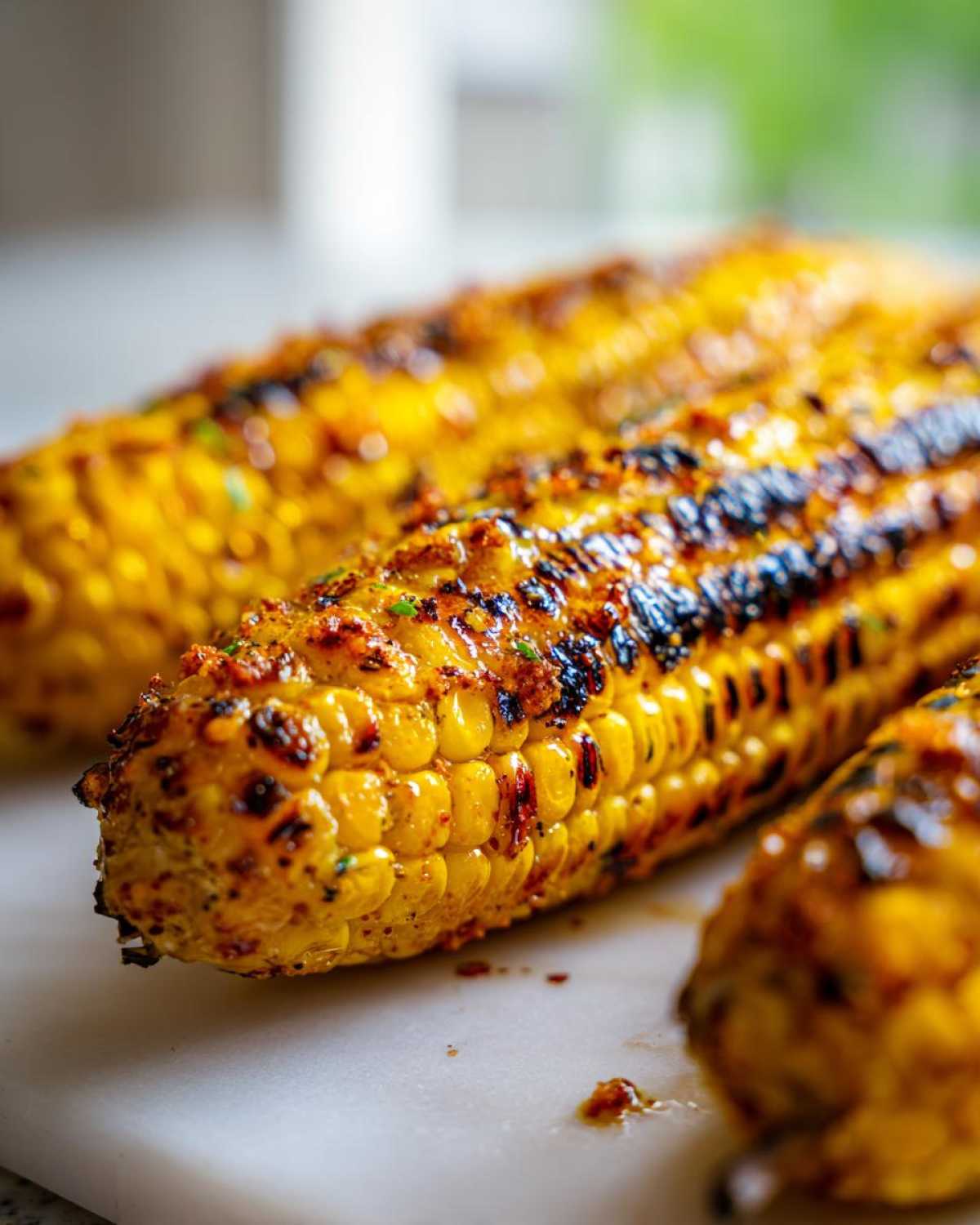 Close-up of perfectly charred Grilled Corn on the Cob with Chili Lime Butter glistening on the kernels.
