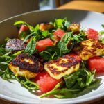 Close-up of a fresh Grilled Halloumi Salad with watermelon chunks, arugula, and mint leaves.