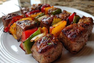 Close-up of perfectly charred Grilled Italian Sausage and Bell Pepper Skewers resting on a white plate.